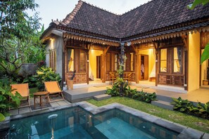 A traditional house with a tiled roof, a swimming pool, and outdoor seating. - Kerjim Wooden Villa (Sukawati)