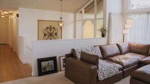 Ein Wohnzimmer mit einer braunen Ledersofa, einem gerahmten Bild und einem dekorativen Wandelement.