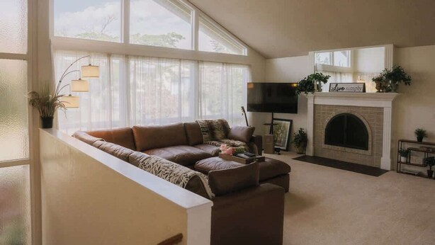 Ein Wohnzimmer mit einem braunen Ledersofa, einem Kamin und einem Fernseher.