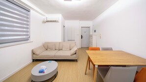 A modern living room with a sofa, a round coffee table, and a wooden dining table with chairs. - Tyms Xujiahui Premium 3BR 2BA APT  (Shanghai)