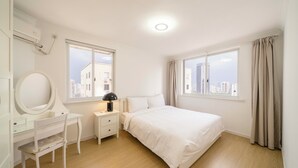 A bedroom with a bed, a desk with a mirror, a nightstand, and a window with curtains. - Tyms Xujiahui Premium 3BR 2BA APT  (Shanghai)