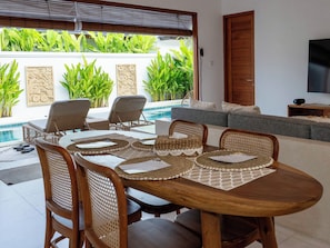 Comedor con vista a la piscina, mobiliario exterior y televisor.