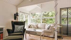 A living room with a sofa, armchair, coffee table, and a bookshelf. - 4 Star Holiday Home in Vaeggerlose (Vaeggerlose)