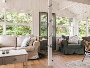 A room with a beige sofa, a green armchair, and a small table with glasses. - 4 Star Holiday Home in Vaeggerlose (Vaeggerlose)