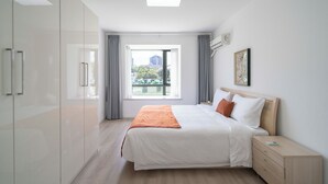 A modern bedroom with a large bed, a bedside table, and a wardrobe. - Tyms Family 3BR 2BA APT Crystal Garden (Shanghai)