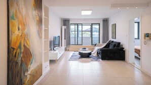 A spacious living room with a large abstract painting, a modern sofa, a coffee table, and a large window with a view of a building. - Tyms Family 3BR 2BA APT Crystal Garden (Shanghai)