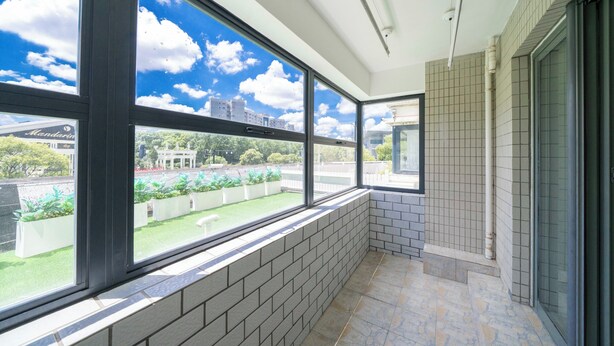 A balcony with large windows, a tiled floor, and a view of a building and greenery. - Tyms Family 3BR 2BA APT Crystal Garden (Shanghai)
