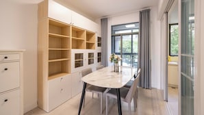 A modern kitchen with built-in cabinets, a marble countertop, and a dining area with chairs and a vase of flowers. - Tyms Family 3BR 2BA APT Crystal Garden (Shanghai)