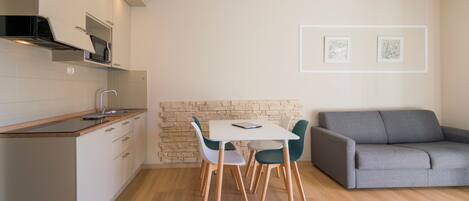 Una cocina moderna con comedor, un sofá gris y dos cuadros en la pared.