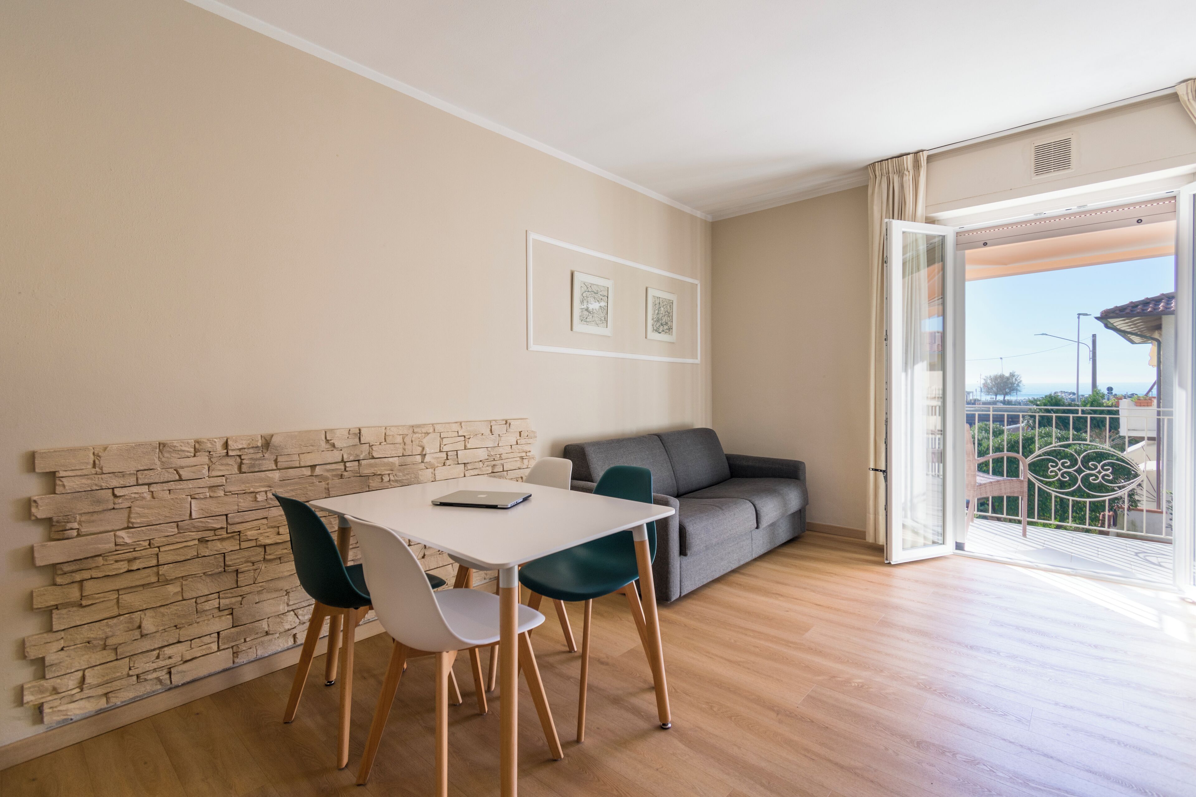 Ein modernes Wohnzimmer mit Essbereich, einem grauen Sofa und einem Balkon mit Blick.