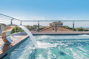 A swimming pool with a water feature, surrounded by a wooden deck and metal railings. - Residence Stella (Massa)