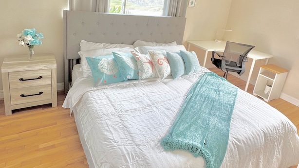 Ein Schlafzimmer mit einem großen Bett, einem Schreibtisch, einem Stuhl, einem Nachttisch und einem Deckenventilator.