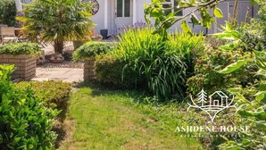 Une maison d’habitation dotée d’un jardin bien entretenu, d’un chemin menant à l’entrée et offrant une vue dégagée sur le quartier environnant.