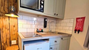 Une cuisine compacte équipée d’un four à micro-ondes encastré, d’un évier et d’un lave-vaisselle.