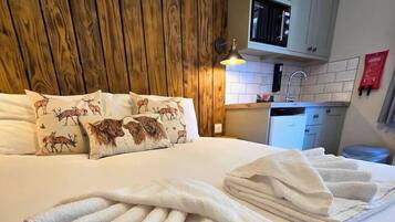 A neatly made bed with rolled white towels, a wooden headboard, and decorative pillows with animal prints.