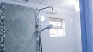 A bathroom with a shower, tiled walls, and a window with bars.