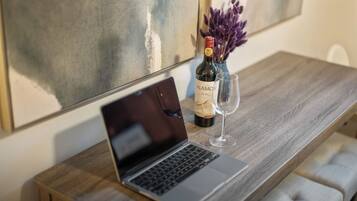 Una laptop sobre una mesa de madera, con una botella de vino y una copa.