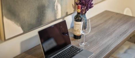 Ein Laptop auf einem Holztisch mit einer Weinflasche und einem Glas.