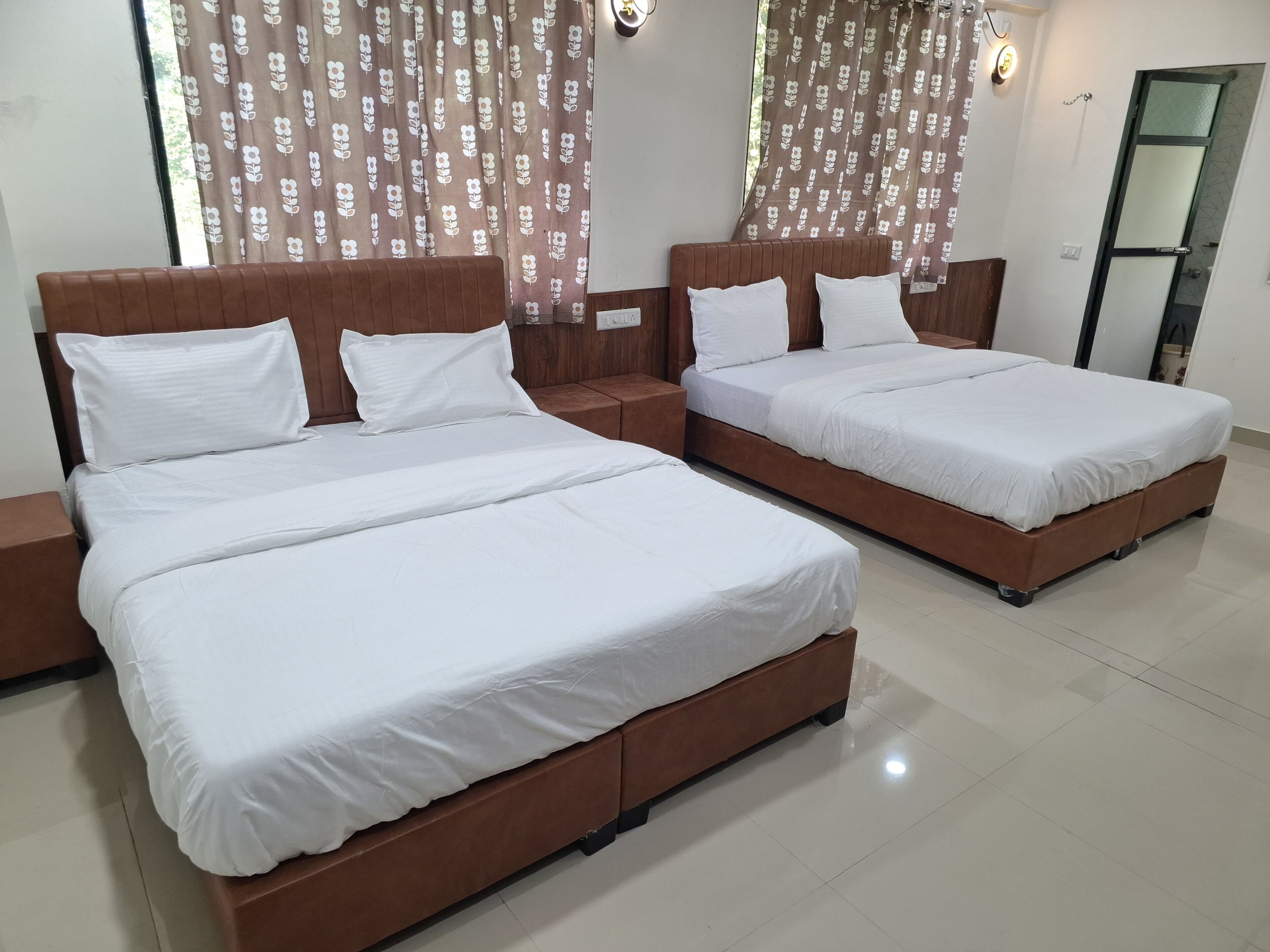 A hotel room with two beds, each with white bedding and wooden headboards.