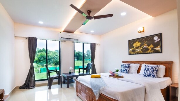 Ein Schlafzimmer mit einem großen Bett, einem Deckenventilator, einem Gemälde und Blick ins Freie.
