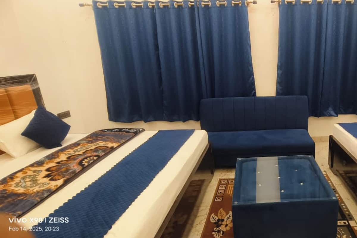 A hotel room with two single beds, a sofa, and a small table.
