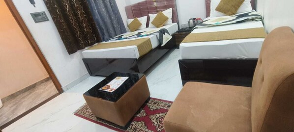 Habitación de hotel con dos camas, una mesita y una silla.