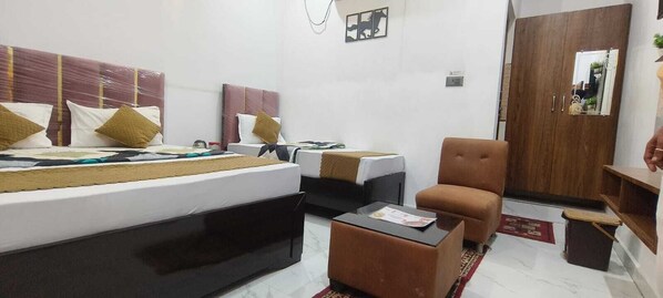 A hotel room with a bed, two bedside tables, a chair, a wardrobe, and a small table with a placemat. - Hotel Prince Palace (Ayodhya)