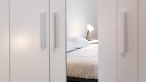A bedroom with a bed, white walls, and a bedside lamp. - Myarenaverona (Verona)
