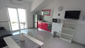 A modern kitchen with red cabinets, a microwave, and a TV. - Berti Sun & Sea Apartments (Hvar)