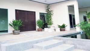 A modern building with a pool, potted plants, and a large door. - ViewPoint Villa (Phuket)