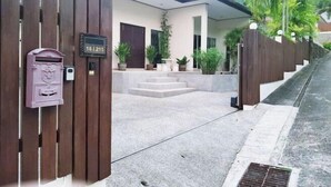 A modern house with a wooden gate, a mailbox, and a number plate. - ViewPoint Villa (Phuket)