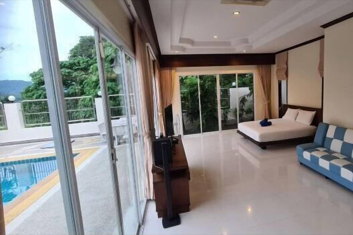 Quarto de hotel moderno com uma grande porta de correr de vidro que dá para uma varanda com piscina.