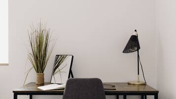A desk with a potted plant, a framed picture, and a desk lamp.
