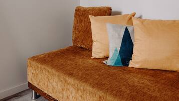 Een bed met een bedekking in bruine textuur en twee kussens, waarvan er een een geometrisch patroon heeft.