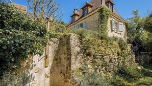 A stone house with a steeply pitched roof, ivy-covered walls, and a large window. - Miramonde, romantic holiday home (Savignac-de-Miremont)