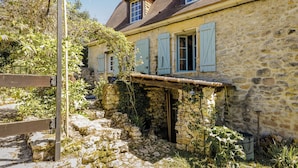 A stone building with a rustic charm, featuring a small garden area with a wooden bench and a stone pathway. - Miramonde, romantic holiday home (Savignac-de-Miremont)
