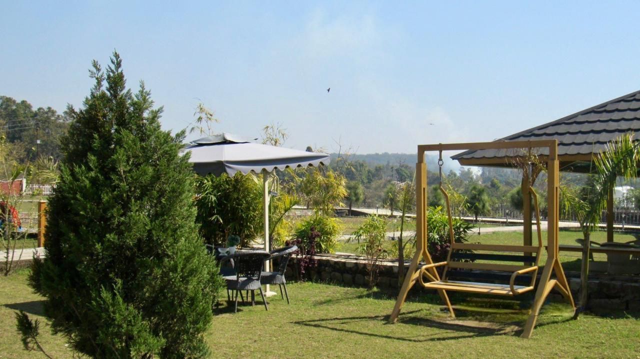 A patio area with a swing set, a covered seating area, and a view of a hilly landscape.