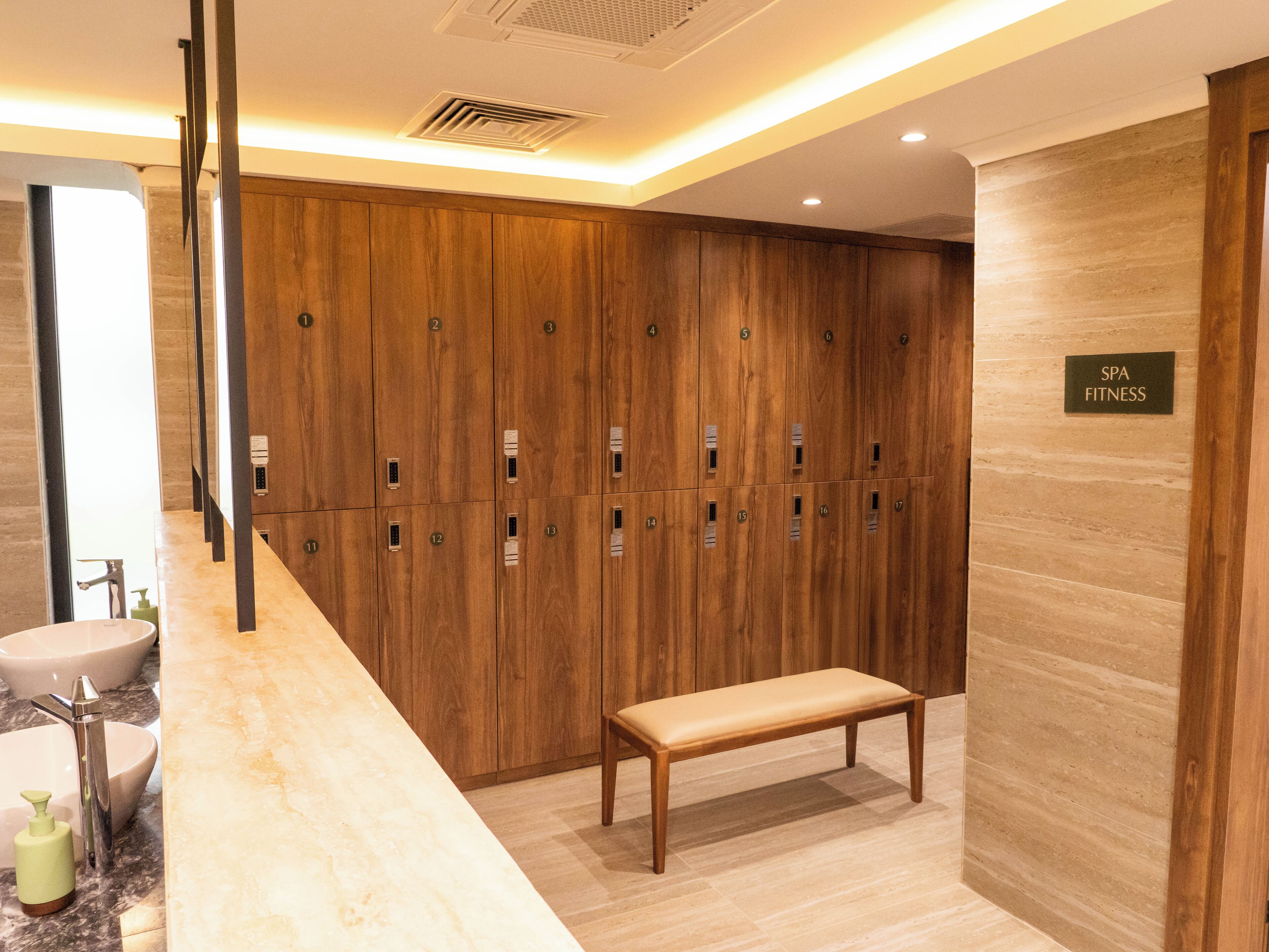 A spa fitness area with wooden lockers, a bench, and a sink with soap dispenser.