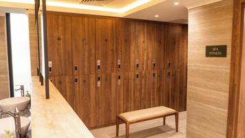 A spa fitness area with wooden lockers, a bench, and a sink with soap dispenser.