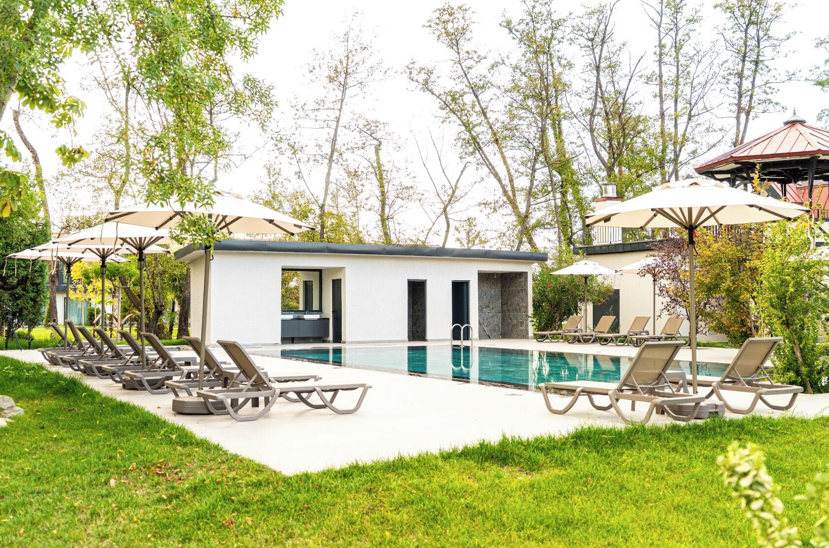 Ein Poolbereich mit Liegestühlen, Sonnenschirmen und einem kleinen Gebäude mit Pool.
