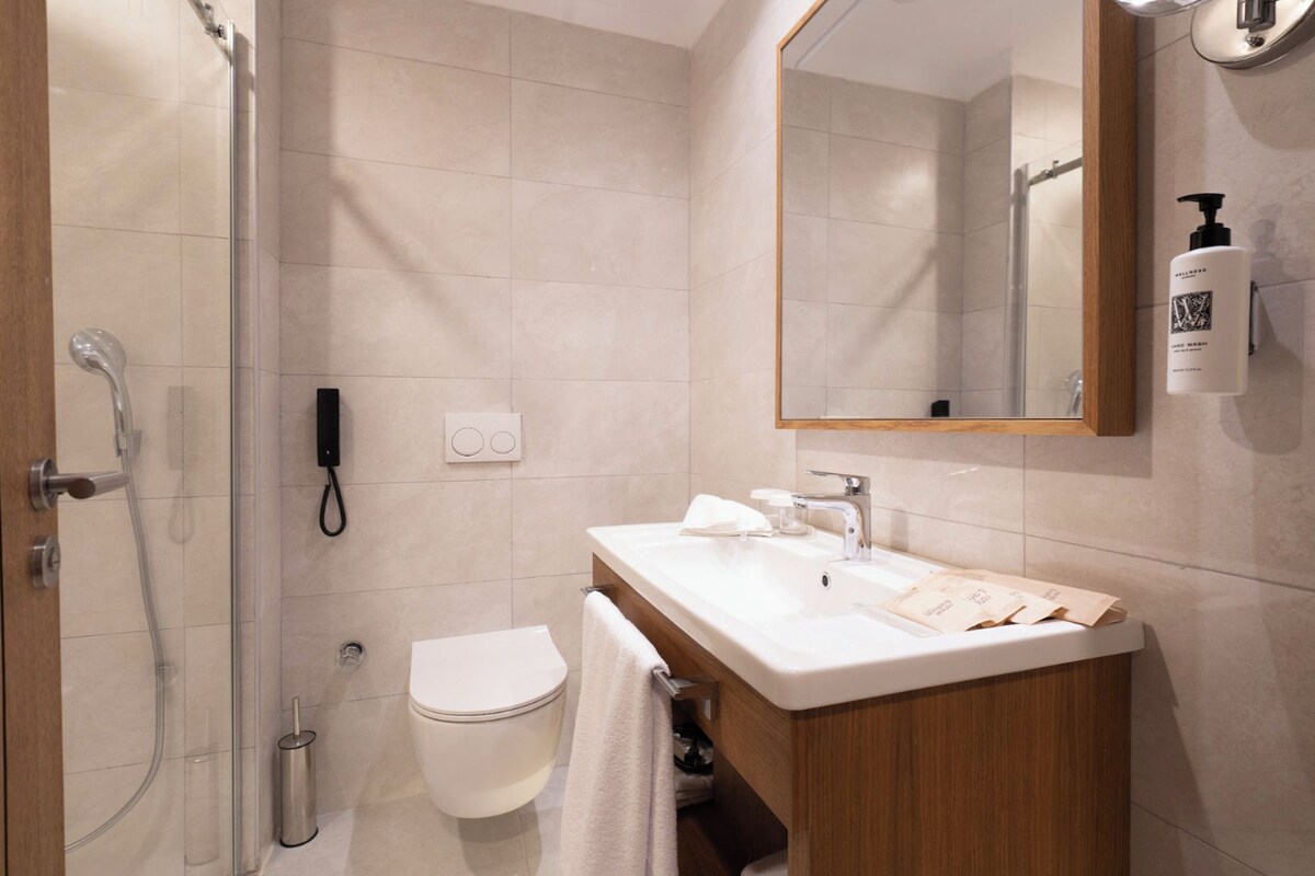 A modern bathroom with a shower, toilet, sink, and a mirror.