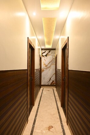 A hallway with wooden paneling, a marble wall, and a ceiling light fixture.