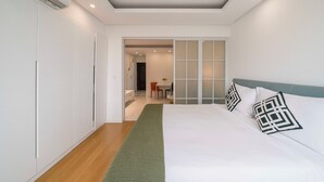 Un dormitorio moderno con una cama grande, un escritorio y una silla al fondo.
