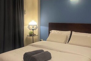 Een hotelkamer met een bed, een nachtkastje met een lamp en een gordijn.