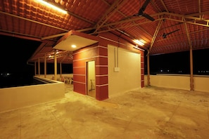 A covered outdoor area with a red brick wall, a door, and a small window. - Mudra Villa & Resort (Nagaon)