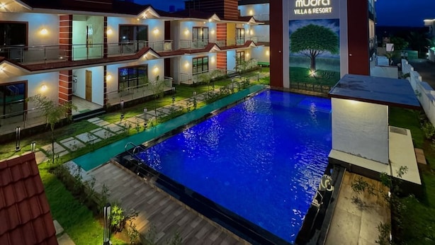 A modern villa and resort with a swimming pool, multiple guest rooms, and a well-lit entrance. - Mudra Villa & Resort (Nagaon)