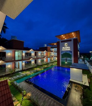 A modern villa and resort with a swimming pool, multiple guest rooms, and a well-lit entrance. - Mudra Villa & Resort (Nagaon)