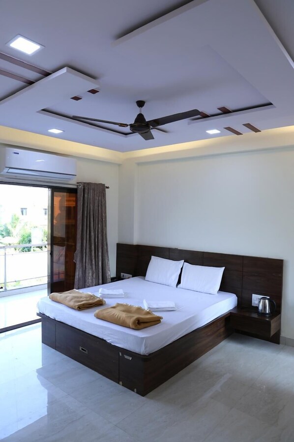 A modern hotel room with a large bed, a ceiling fan, and a view of the outdoors.