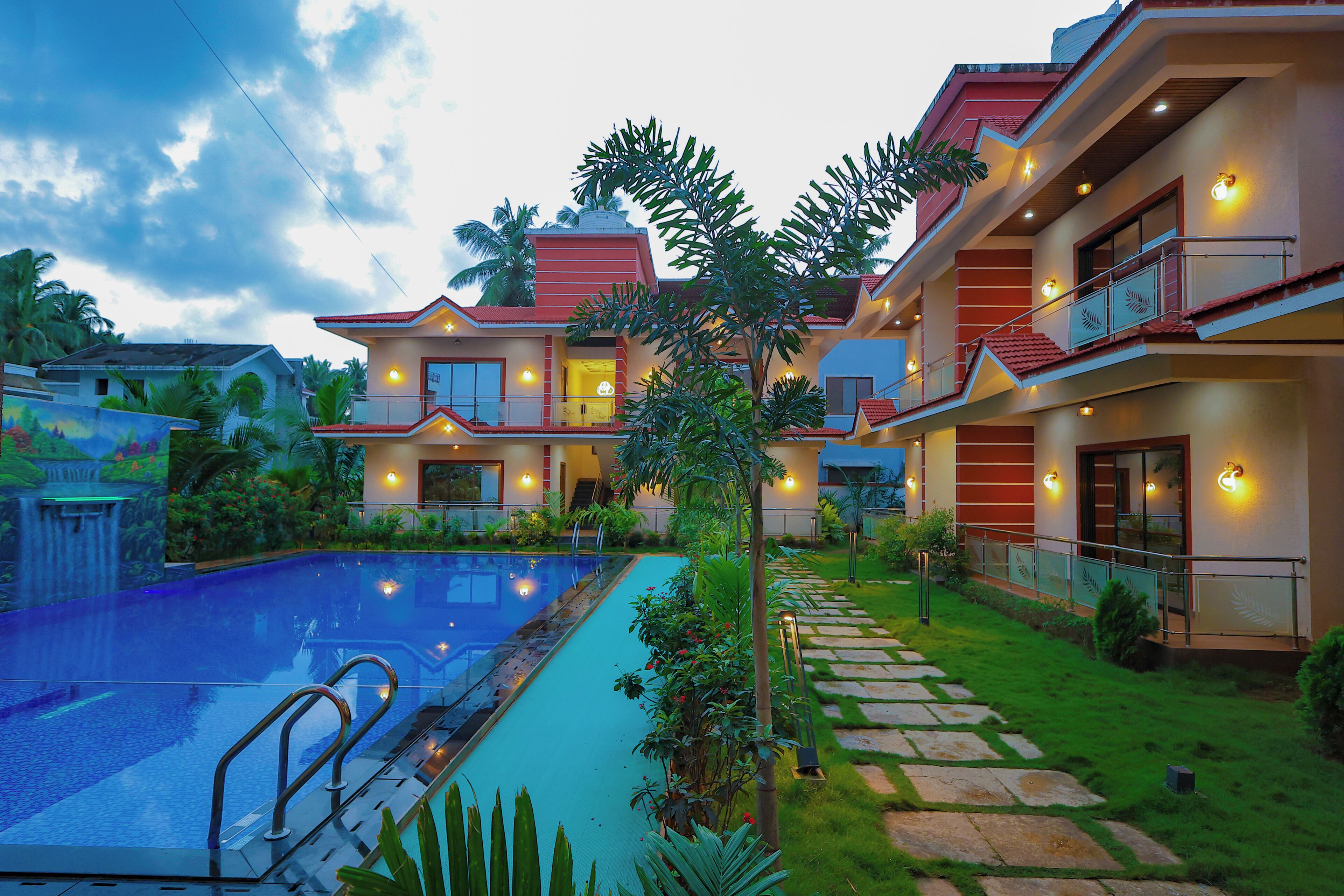 A hotel with a swimming pool, a well-maintained garden, and a two-story building with balconies.