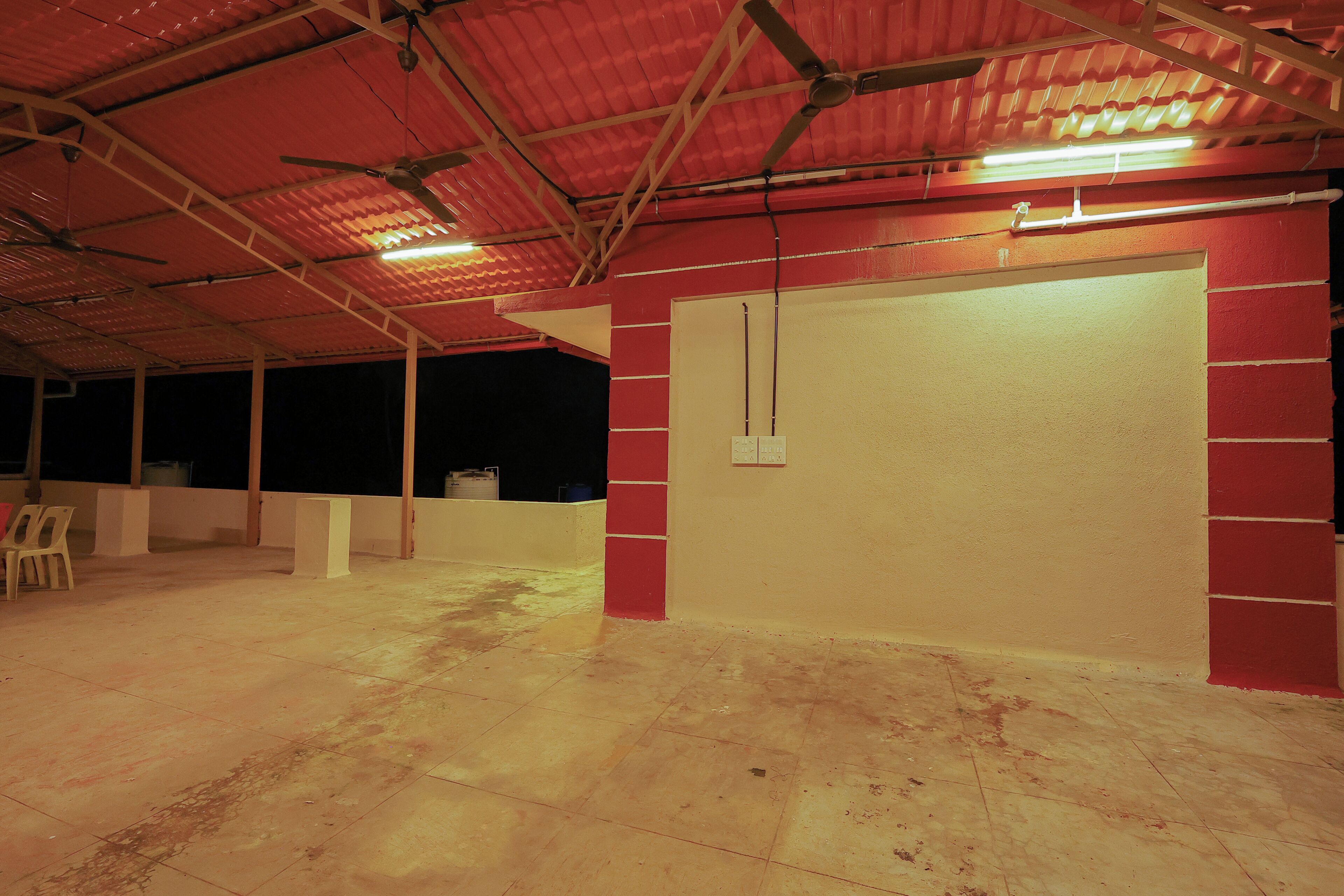 An indoor space with a high ceiling, exposed beams, and a tiled floor.